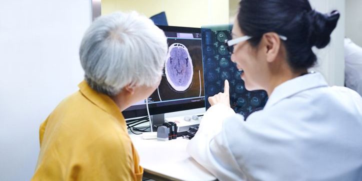 Doctor and Senior Female Patient Checking MRI film at Doctor's Office stock photo