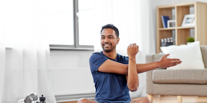 Man training and stretching arm at home