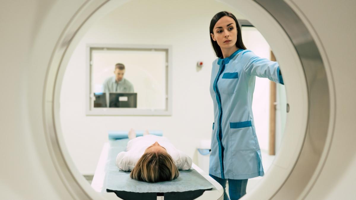 Patient getting a PET scan with doctor next to them 