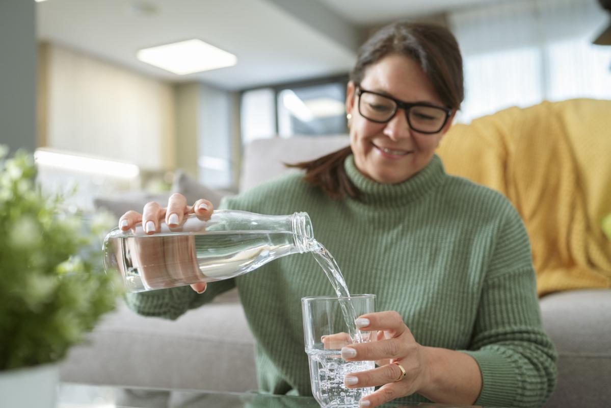 Woman filling glass with drinking water